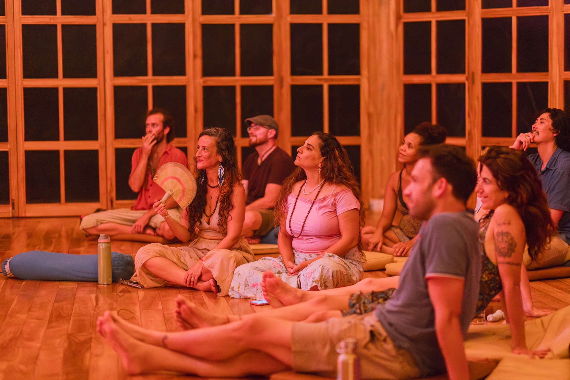 Residents gathered on the wooden floor of the hall in warm evening light